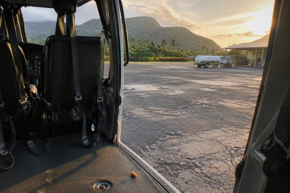 A helicopter cabin interior with empty passenger seats and a wide open door