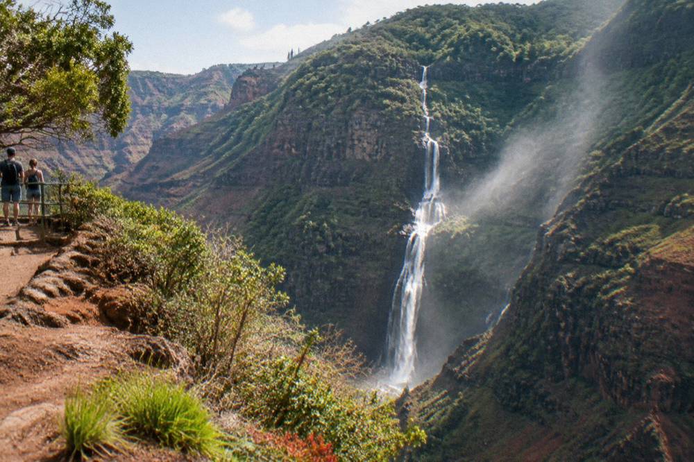A ribbon of waterfalls spilling down a dark green cliff face inside a deep canyon