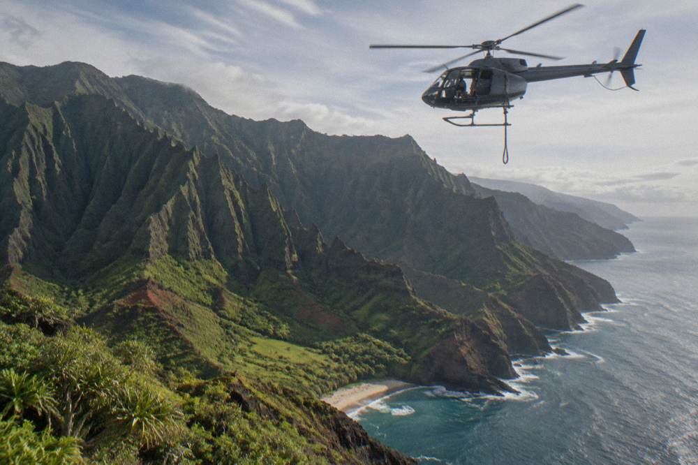 A doors-off helicopter cabin above a canyon and coastline