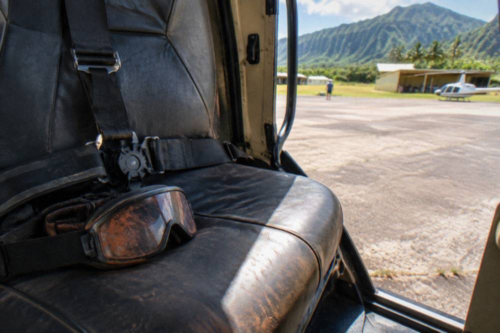 Flight goggles and a harness strap resting on a helicopter seat