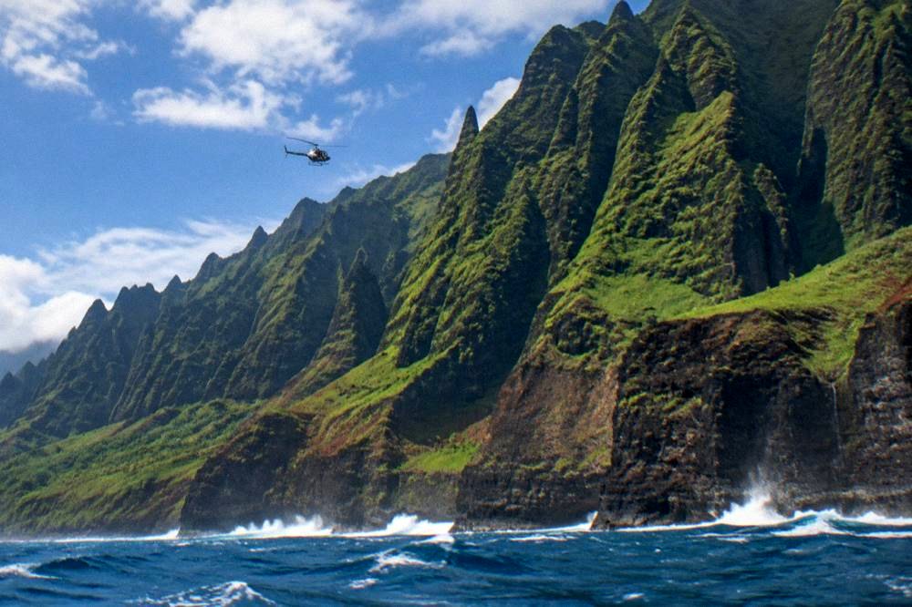 Sharp green sea cliffs rising from the ocean along a rugged coast