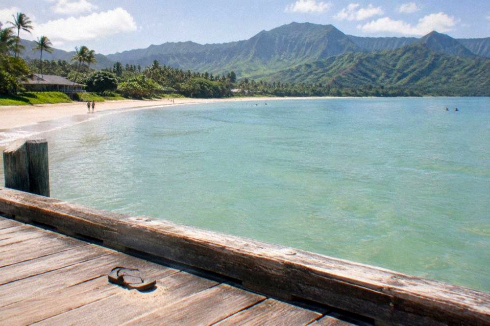 A golden sand beach curving along a green shoreline with turquoise water