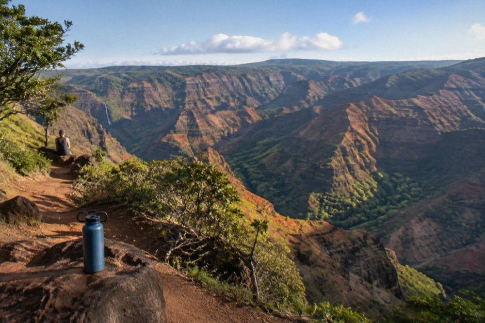 A deep red and green canyon with layered ridges under a bright sky