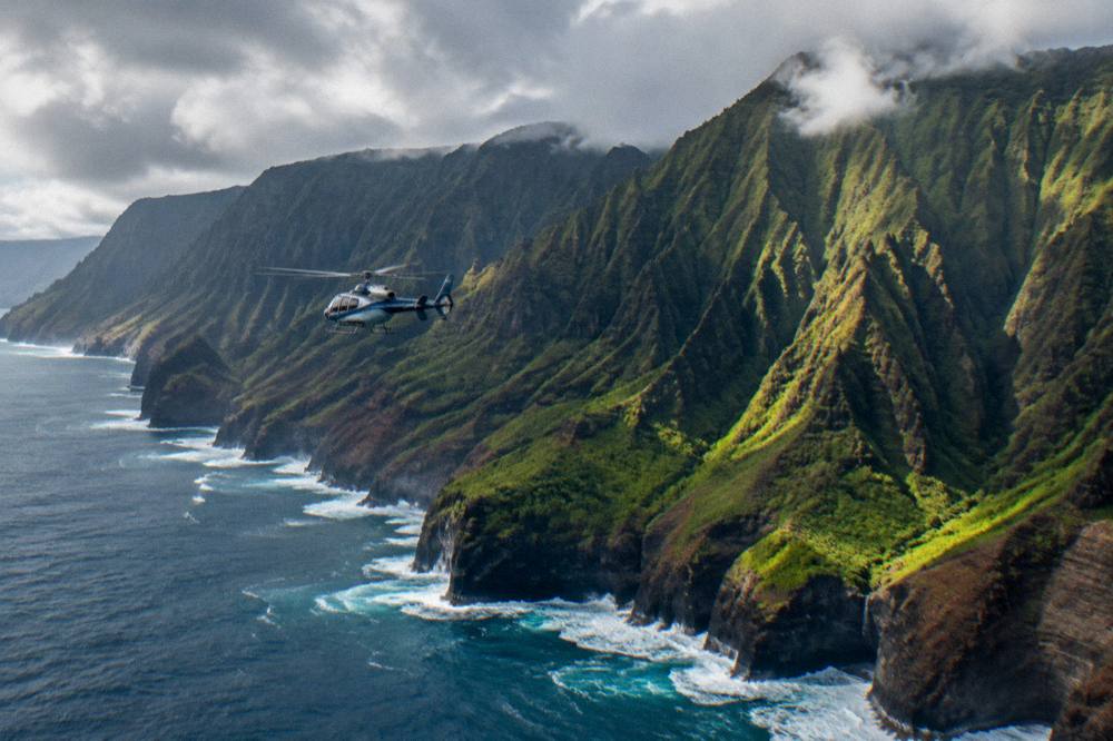 A helicopter flying above a coastline of tall sea cliffs