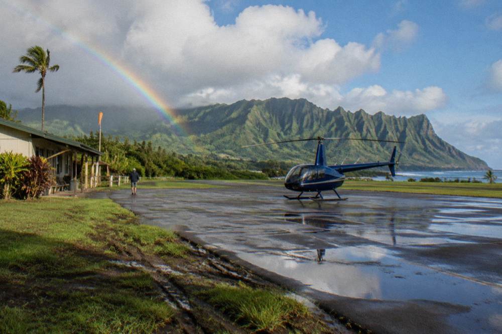 Coastal plateau airfield with a helicopter parked beside a paved strip and green cliffs in the distance