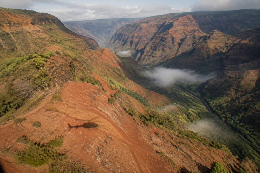 Morning light across a wide canyon with mist in the valley floor seen from the air