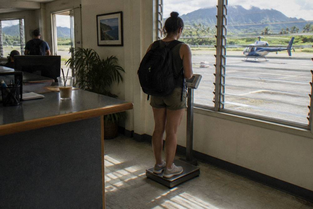 A passenger being weighed at a check-in counter before a helicopter tour