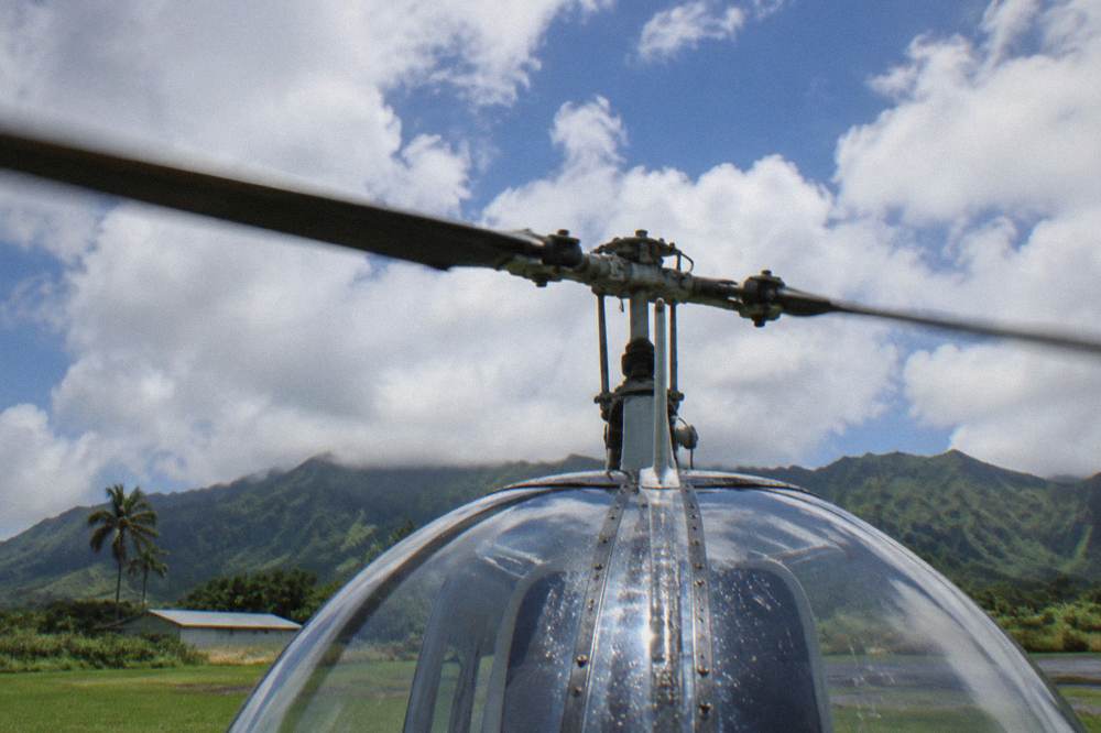 A close view of a helicopter rotor head against a bright sky