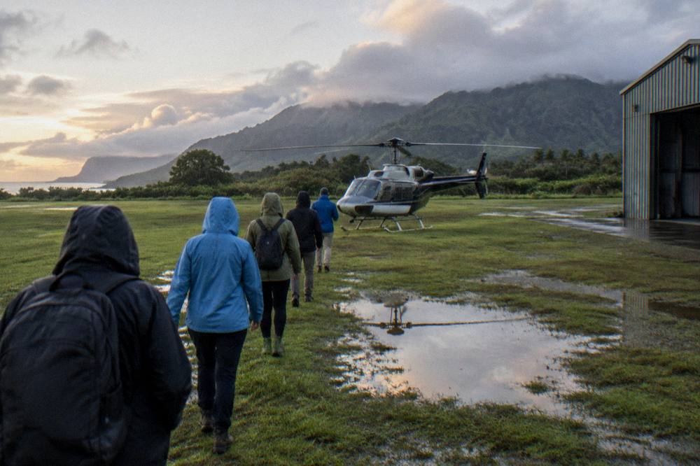 Passengers walking toward a helicopter across a heliport landing pad