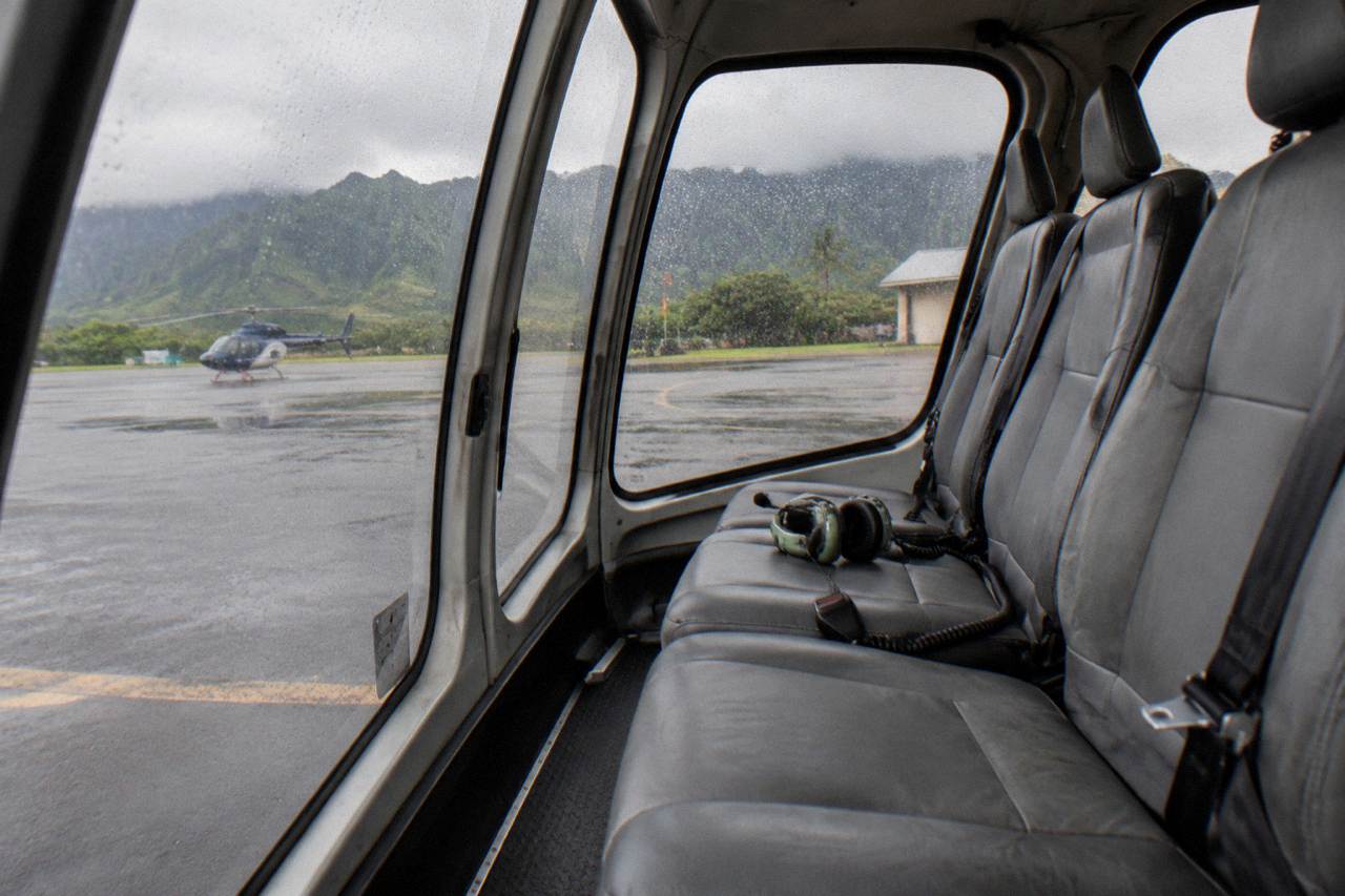 A helicopter cabin interior showing rows of passenger seats beside large window panels