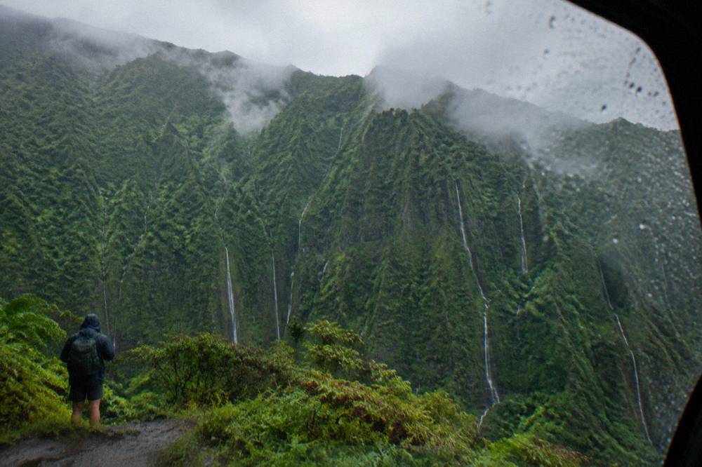 Mist and thin waterfalls streaming down steep green crater walls