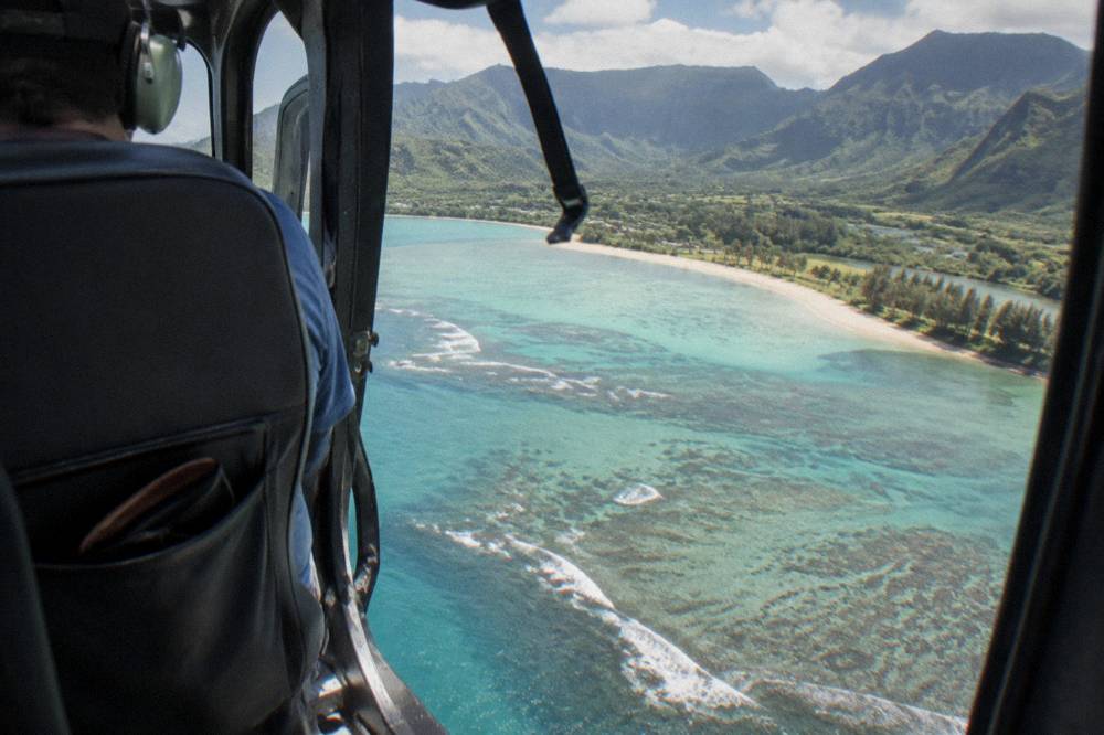 A passenger cabin of a helicopter with open doors showing ocean below