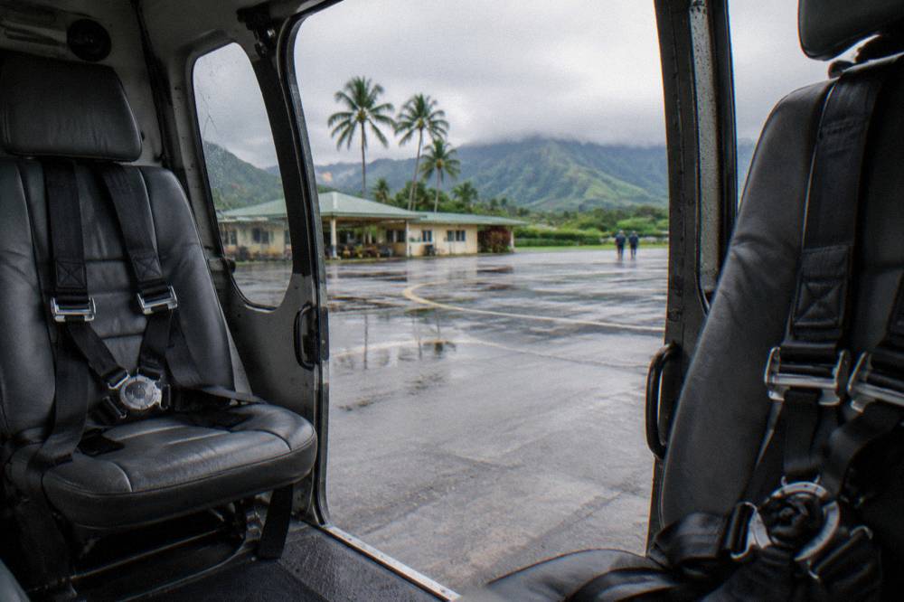 The open cabin door of a helicopter showing two empty leather seats and harnesses