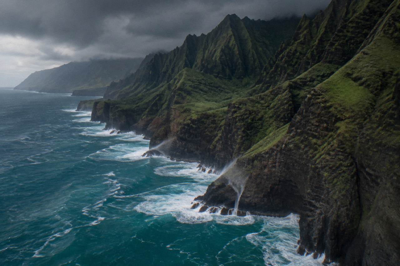 Tall sea cliffs along a green coastline with ocean waves below