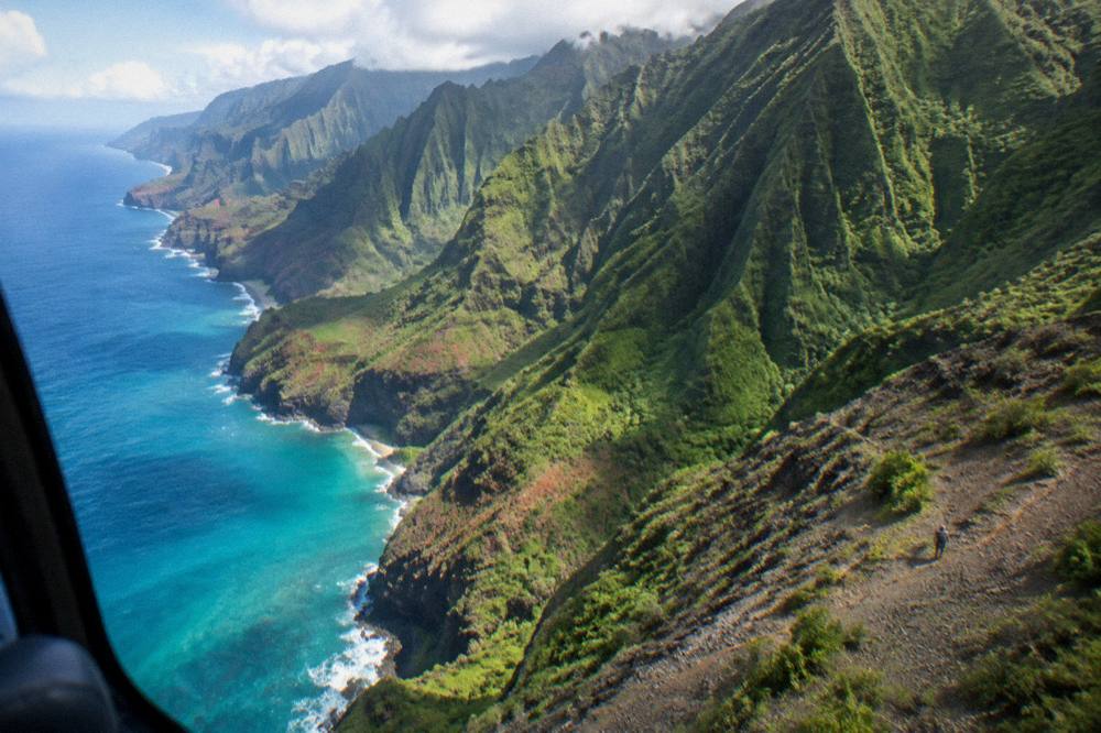 Na Pali Coast's dramatic sea cliffs and turquoise water seen from a private helicopter