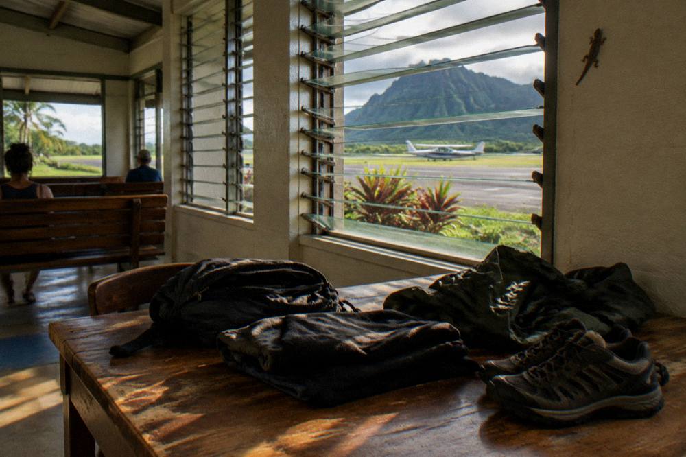 A minimal packing set of dark clothing, jacket and shoes ready for a helicopter flight